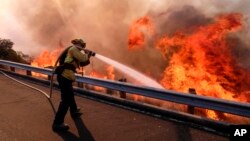 A firefighter battles a fire in Simi Valley, California, Nov. 12, 2018. (AP Photo/Ringo H.W. Chiu)