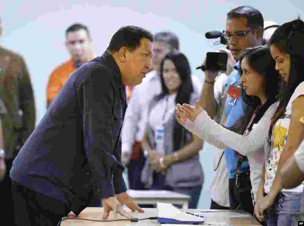 Chavez berbicara dengan para pekerja di sebuah tempat pemungutan suara sebelum memberikan suaranya pada pemilihan presiden di Caracas, 7 Oktober 2012.