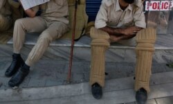 Kashmiri policemen sit outside a closed shop in Srinagar, Indian-controlled Kashmir, Aug. 22, 2019.