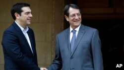 Cyprus' President Nicos Anastasiades, right, shakes hands with Greek Prime Minister Alexis Tsipras at the Presidential Palace following their meeting in the capital Nicosia, Feb. 2, 2015.
