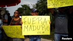 Warga memegang poster-poster saat menunggu kedatangan truk bantuan kemanusiaan internasional untuk Venezuela dekat jembatan penyeberangan Tienditas antara Colombia dan Venezuela, di Cucuta, Kolombia, 7 Februari 2019. 