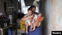 Jaqueline (L), 25, holds her five-month-old twins, Laura (R) and Lucas at their house in Santos, Sao Paulo state, Brazil, April 20, 2016. 