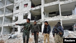FILE - Fighters of the Kurdish People's Protection Units (YPG) stand on the debris of a damaged building in the northern Syrian town of Kobani, Jan. 28, 2015.