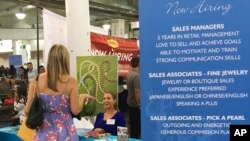 FILE - A woman speaks to Maui Divers Jewelry representatives at a job fair in Honolulu.