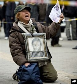 中国的一位访民手持上访信下跪伸冤(资料照片)