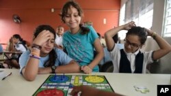 In this Friday, Oct. 13, 2017 photo, girls play a board game at the Ramon Marin Sola Elementary School, which opened its doors as a daytime community center after the passing of Hurricane Maria in Guaynabo, Puerto Rico. (AP Photo/Carlos Giusti)