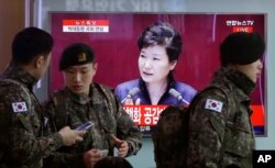 South Korean army soldiers pass by a TV screen showing the live broadcast of South Korean President Park Geun-hye's speech, at the Seoul Railway Station in Seoul, South Korea, Tuesday, Feb. 16, 2016.