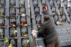 FILE - A man places flowers at a monument to the so-called "Heavenly Hundred," anti-government protesters killed during Ukraine's 2014 Maidan revolution, in Kyiv, Ukraine, Nov. 21, 2019.