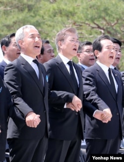 문재인(가운데) 대통령이 18일 광주 국립 5·18 민주묘지에서 열린 제37주년 5·18 민주화운동 기념식에서 '임을 위한 행진곡' 작곡가인 김종률(왼쪽) 광주문화재단 사무처장, 정세균(오른쪽) 국회의장과 함께 손을 잡고 노래를 제창하고 있다.