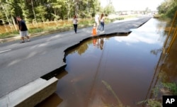 Pedestrians walk down Dorchester Road at Sawmill Branch Canal as it begins to wash away due to floodwaters near Summerville, S.C., Oct. 6, 2015. Residents are concerned that the Ashley river will continue to rise as floodwaters come down from Columbia.