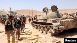 Free Syrian Army fighters inspect munitions and a tank that belonged to forces loyal to Syria's President Bashar al-Assad after they seized Khanasir, August 26, 2013. 