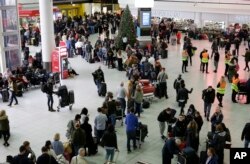 People queue at Gatwick airport, near London, as the airport remains closed with incoming flights delayed or diverted to other airports, after drones were spotted over the airfield last night and this morning, Dec. 20, 2018.