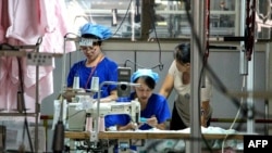 FILE - This photo taken on August 29, 2019 shows workers producing cloth that will be exported to the US at a textile factory in Binzhou, China's eastern Shandong province. 