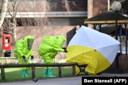 Emergency services in green biohazard suits affix a tent over the bench where poisoning victims were found on March 4 in critical condition at The Maltings shopping centre in Salisbury, southern England, on March 8, 2018.