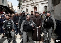Israeli police forces escort Franciscan priests along the Via Dolorosa (Way of Suffering) in Jerusalem’s Old City during the Good Friday procession on March 25, 2016.
