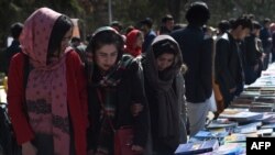 FILE - Visitors browse a book exhibition to mark International Women's Day at Kabul University, March 8, 2020. The Taliban say women have nothing to fear under their rule, but that's not how many educated Afghan women see it.