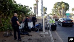 FILE - Police officers remove a tent left by homeless people, Sept. 25, 2017, during efforts to sanitize neighborhoods to control the spread of hepatitis A, in San Diego.
