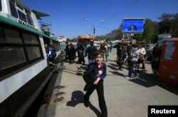 People walk under an electronic screen showing nationwide call-in attended by Russian President Vladimir Putin on a street of the Black Sea port of Sevastopol, Crimea, April 14, 2016.