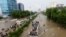 FILE - People sit atop a bus roof while others wade through the flooded road during monsoon rain, in Karachi, Pakistan Aug. 27, 2020. 