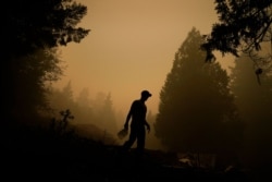 Aaron Cleys holds a jug of water he was using to douse hot spots at a home destroyed by the the Riverside Fire, Sept. 11, 2020, in Estacada, Ore.
