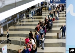 FILE - A long line of travelers wait for the TSA security check point at O'Hare International airport, in Chicago.