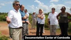 លោកស្រី Elizabeth Becker (កណ្តាល) ឈរ​ជាមួយ​លោក ឆាំង យុ នៅ​គណៈប្រតិភូ​មួយ​ឈរ​នៅ​ក្បែរ​រណ្ដៅ​​គ្រាប់​បែក​ B52 នៅ​ជិត​អាកាសយានដ្ឋាន​សាងសង់​ដោយ​ចិន នៅ​ខេត្ត​កំពង់ឆ្នាំងកាល​ពី​ថ្ងៃ​ទី​២៤ ខែ​តុលា ឆ្នាំ​២០១២។ (Photo by Nhean Socheat)