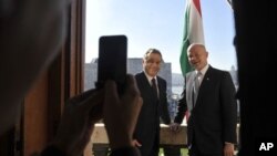 British Foreign Minister William Hague (L) and Hungarian Prime Minister Viktor Orban pose for photographers on a balcony during their meeting at Orban's office in the Parliament building in Budapest, Hungary, October 4, 2012.