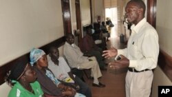 FILE - A health worker from The AIDS Support Organization (TASO) speaks with patients waiting for treatment in Kampala, Uganda.
