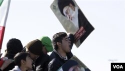 Para remaja Iran ikut meramaikan perayaan HUT Revolusi Islam sambil membawa poster Ayatollah Ali Khamenei di Teheran (11/2).
