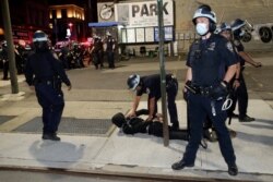 FILE - Police officers cuff a suspect during a protest against police brutality, in New York City, June 1, 2020.