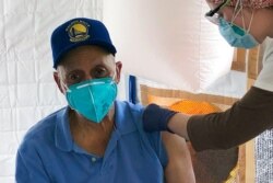 FILE - Martin Auzenne, 73, receives a COVID-19 vaccine shot from a health care worker at a vaccination site in the Bayview neighborhood of San Francisco, Feb. 8, 2021.