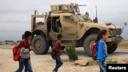 រូបឯកសារ៖ សិស្សសាលាដើរកាត់រថយន្តល្បាតរបស់អាមេរិក នៅក្រុង Hasakah ប្រទេសស៊ិរី។ 