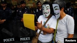 បាតុករ​ប្រឆាំង​រដ្ឋាភិបាល​ពាក់​ស្បែក​មុខ​និង​ប្រើ​ឧបករណ៍​ iPad នៅ​មុខ​ក្រុម​ប៉ូលិស​បង្ក្រាប​កុប្បកម្ម​ក្នុង​អំឡុង​បាតុកម្ម​មួយ​នៅ​​ខាង​ក្រៅ​ផ្សារ​ទំនើប​មួយ​នៅ​រាជធានី​បាងកក​កាល​ពី​ថ្ងៃ​ទី​៩​ខែ​មិថុនា​ឆ្នាំ​២០១៣។