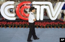 សន្តិសុខ​ម្នាក់​កំពុង​ដើរ​កាត់​ឡូហ្គោ​ទូរទស្សន៍​ចិន CCTV ដែល​ឥឡូវ​នេះ​បាន​ប្តូរ​ទៅ​ជា​ CGTV ក្នុង​ទីក្រុង​ប៉េកាំង​ប្រទេស​ចិន។