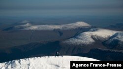 Peneliti Ninis Rosqvist di puncak selatan Kebnekaise di Swedia tampak menggunakan peralatan untuk melakukan pengukuran ketinggian gunung es. Ketinggian gunung-gunung es di Swedia menyusut dengan cepat akibat mencairnya lapisan gletser karena pemanasan global. 