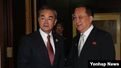 25일 라오스 비엔티안에서 열린 북-중 양자회담에 앞서 중국 왕이 외교부장(왼쪽)이 북한 리용호 외무상과 악수하고 있다.