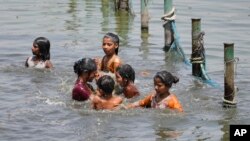 Anak-anak bermain air di Sungai Gomati saat India utara dihantam gelombang panas yang hebat di Lucknow, negara bagian Uttar Pradesh, India, 19 April 2023. (Foto: AP)