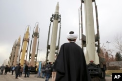 FILE - An Iranian clergyman looks at domestically built surface-to-surface missiles displayed by the Revolutionary Guard in a military show marking the 40th anniversary of the Islamic Revolution, at Imam Khomeini Grand Mosque in Tehran, Iran, Feb. 3, 2019.