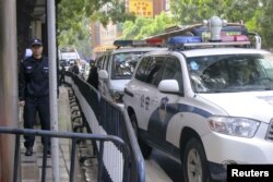 Police cars are parked as policemen stand guard outside a court in the southern Chinese city of Guangzhou, Jan. 29, 2016.