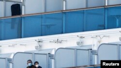 신종 코로나바이러스 집단 감염이 발생한 일본 가나가와현 요코하마 정박 크루즈선에서 13일 탑승자 2명이 마스크를 쓰고 밖을 내다보고 있다. 