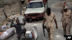 Seorang pria mengangkat tangannya di tengah polisi yang berpatroli di jalanan di pusat kota Port-au-Prince, Haiti, pada 22 September 2021. Warga membuat barikade sebagai bentuk protes terhadap dugaan pembunuhan yang dilakukan polisi pada minggu lalu. (Foto: AP/Rodrigo Abd)