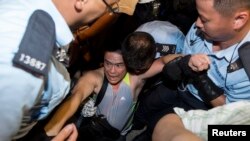 Seorang pemrotes diciduk polisi setelah bermalam di distrik finansial utama Hong Kong (2/7). 