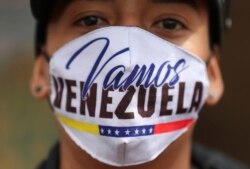 A Venezuelan migrant wearing a face face mask that reads in Spanish "Let's go Venezuela" walks toward the Venezuelan border after a lockdown ordered by the government, in Bogota, Colombia, Monday, April 6, 2020.