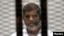 FILE - Ousted Egyptian President Mohamed Mursi is seen behind bars during his trial at a court in Cairo, May 8, 2014. 
