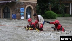 Firefighters rescue a stranded woman on a flooded street following heavy rainfall in Chengdu, Sichuan province, China, July 11, 2018.