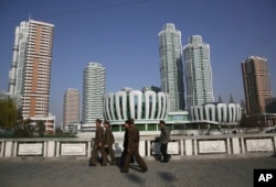 North Koreans walk past Ryomyong Street, the newest residential development in Pyongyang, North Korea, April 11, 2017. North Korean Premier Pak Pong Ju told the Supreme People's Assembly that a priority for the Cabinet this year would be improving the country's standard of living.