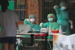 FILE - Medical personnel wearing protective gear guide people at a rapid coronavirus testing center after the infection alert rose to level 3 in Taipei, Taiwan, May 18, 2021.