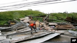 Seorang petugas tengah mengambil potongan papan dari bangunan yang hancur akibat hempasan angin kencang yang dipicu oleh topan Mangkhut yang menyapu kawasan kota Tuguegarao, provinsi Cagayan province, northeastern Filipina, Sabtu (15/9).