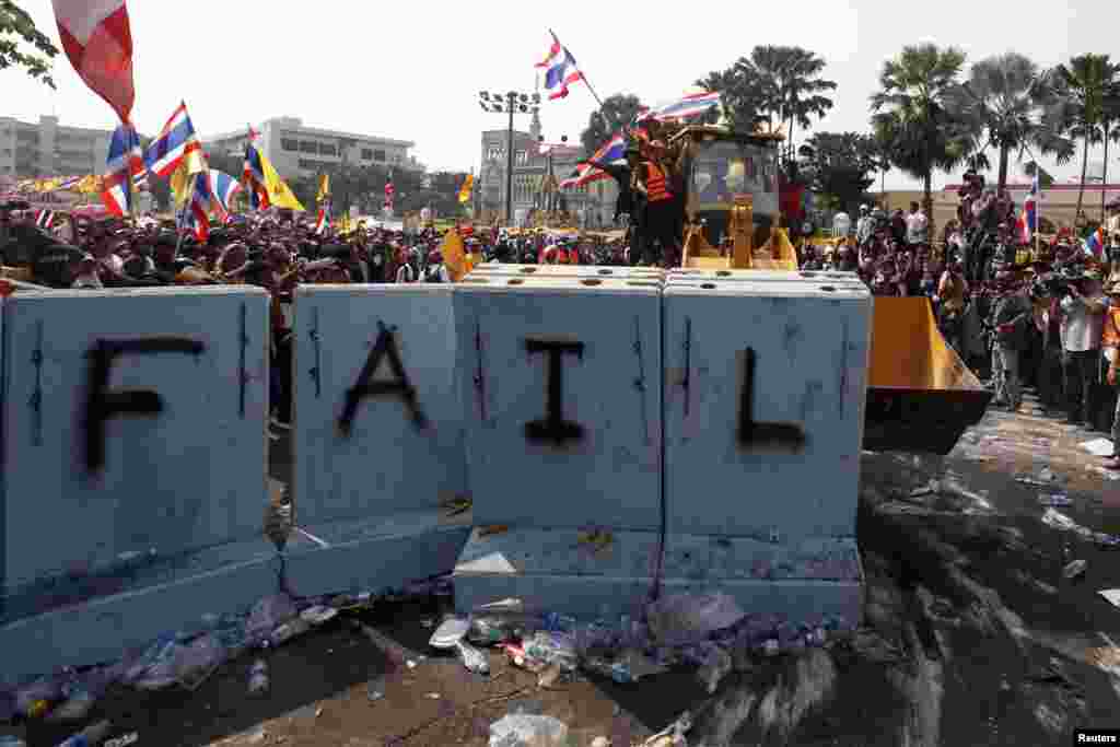 Anti-government protesters use a front loader to knock down a concrete barricade outside the Government House in Bangkok, Dec. 9, 2013. 