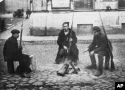 In this photo taken in Oct. 1917, provided by Russian State Archive of Social and Political History, armed revolution workers warm themselves at a bonfire in St.Petersburg, Russia. From left: Ivanov, Yarosh and Gribovsky.